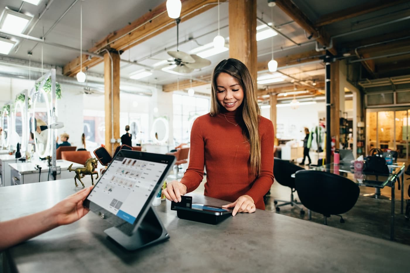 Small business owner taking a card payment on a tablet point-of-sale at her shop counter